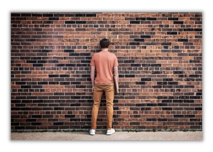 man with low esteem banging head against brick wall